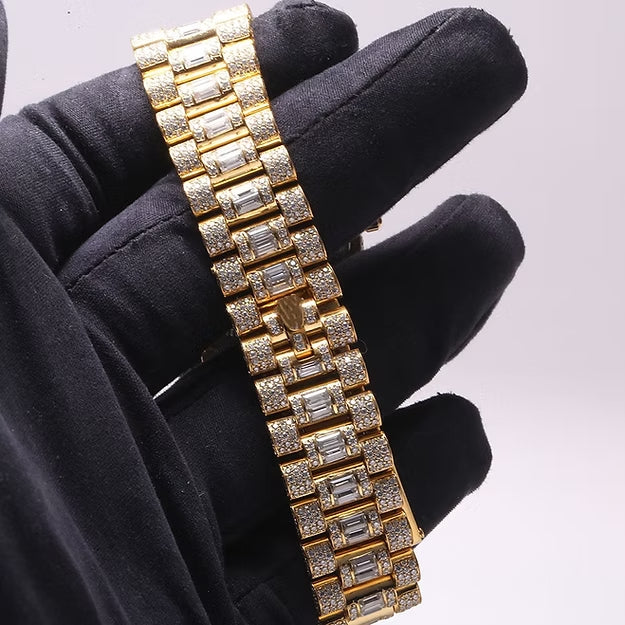 Gold bracelet with diamonds held by a black gloved hand against a white background